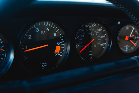Tablero de auto deportivo aleman. Indicadores de vueltas, velocidad y hora. Fondo negro agujas naranjas. RPM, MPH. Odometro, Tacometro.