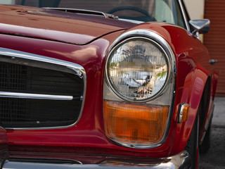 Faro delantero de auto aleman antiguo. Auto cl&aacute;sico de color rojo.