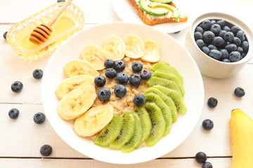 Oatmeal, granola with bananas, kiwi fruits, blueberries and honey.Tasty  vegetarian breakfast.Healthy food or diet concept.  top view. Flat lay. 