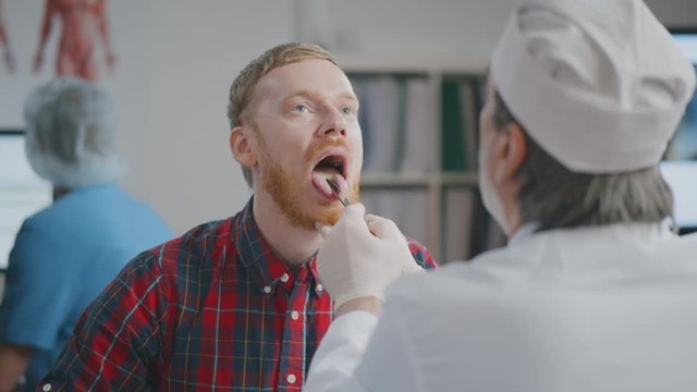 Otolaryngologist examining patient throat with swollen glands