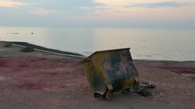 An old useless trash can garbage bin on top of a viewpoint near sea