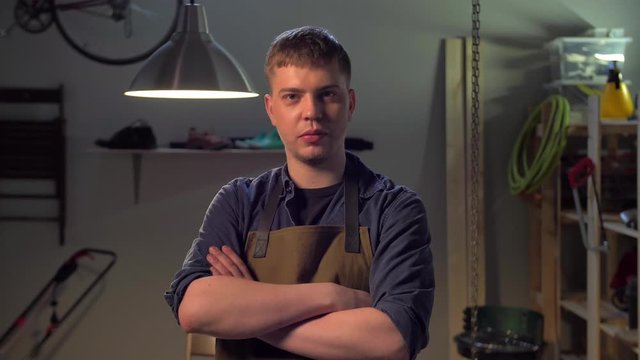 Man in apron stands and looks at the camera