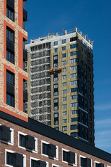 Finishing of the building, wall insulation, in high- rise residential complex in Moscow with the blue sky background