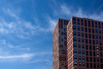 Two high rise residential buildings with blue sky with white clouds background