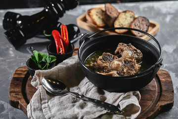 Shurpa soup in a cast-iron pot on the table on a gray background. Traditional oriental cuisine.