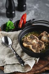 Shurpa soup in a cast-iron pot on the table on a gray background. Traditional oriental cuisine.