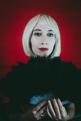 Vintage style portrait of a blonde woman covering by a hand fan
