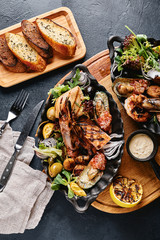 Assorted seafood on plates. Beautiful composition on a served seafood table, squid, shrimp, salmon steak and octopus. Food photo, low key, traditional Italian cuisine. Top view, save the space