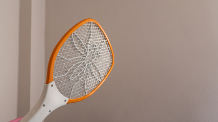 A mosquito swatter in the hand Going to hit mosquitoes by the wall