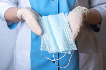 The nurse holds protective face masks in her hands. Hands are wearing disposable medical gloves. Remedies for viruses, diseases, flu and coronavirus