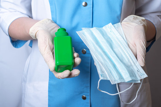 The nurse is holding a bottle of antiseptic and protective face masks. Personal hygiene items. Hands are wearing disposable medical gloves. Remedies for viruses, diseases, flu and coronavirus - Powered by Adobe
