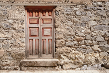 Wooden door at the entrance of a traditional clay house at a sunny day on a street of Huancaya, Lima Region, Peru