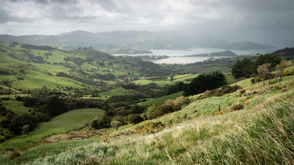 Storm approaching a valley with green rolling hills, shot at Banks Peninsula, New Zealand