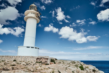 Fototapeta na wymiar Lighthouse on the Formentera island, Spain, the blue sky with white clouds, without people, rocks, stones, sunny weather