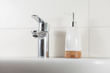 Sink with soap dispenser in bathroom. Corona virus hygiene concept.