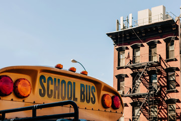 Detail of the text school bus on the front of a bus and in the background a typical new york city...