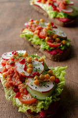 open sandwich with beetroot hummus with vegetables and tomato sauce. Healthy vegan food concept.