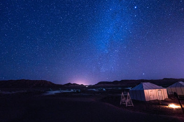 base camp in the middle of the desert on a starry night crossed by a shooting star - obrazy, fototapety, plakaty