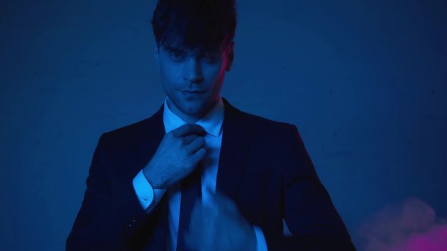 handsome man in suit showing hush sign on blue with smoke