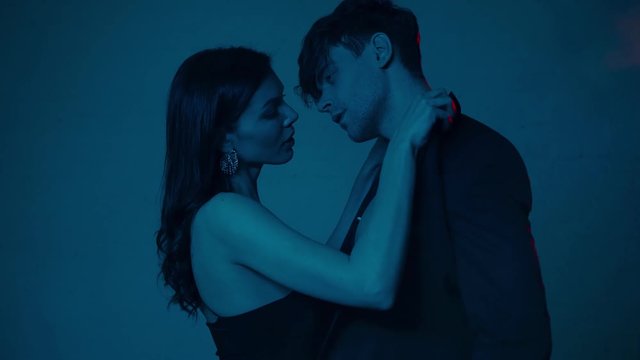 side view of woman undressing handsome man on blue