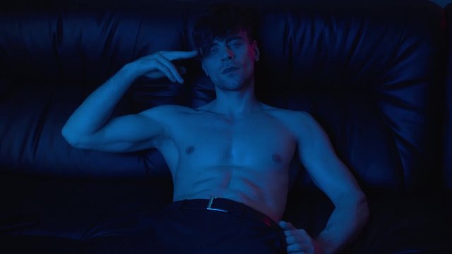handsome and muscular man gesturing and lying on sofa