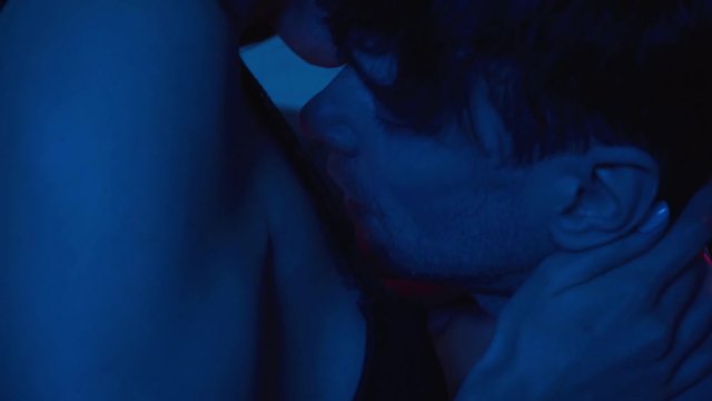 handsome man kissing seductive young woman on blue