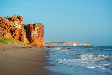 Colorful cliffs, dunes and small sailing boat early morning on the beach of Peroba, Icapui,...