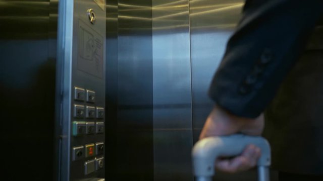 rack focus of businessman pressing buttons in elevator