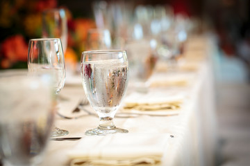 Ice cold water in a glass on a long table set for a party