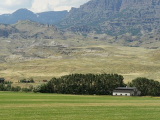 Fototapeta premium Beautiful Wyoming landscape with green plains and tall rugged mountains in the background.