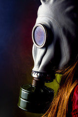 girl in red dress wearing a gas mask sits in smoke with red blue and yellow lights