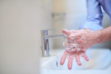 coronavirus male wahing hands in bathroom