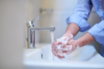 coronavirus male wahing hands in bathroom