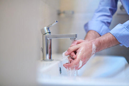 coronavirus male wahing hands in bathroom