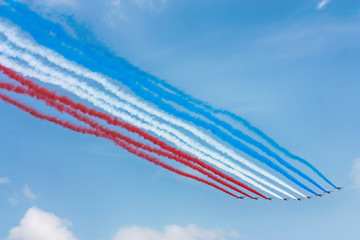 Cores da bandeira da frança feita de fumaça por aviões em dia limpo com céu azul. - obrazy, fototapety, plakaty