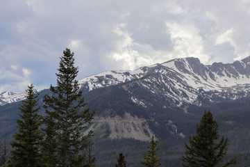 A view of the snow covered Colorado mountains and cloudy skies 