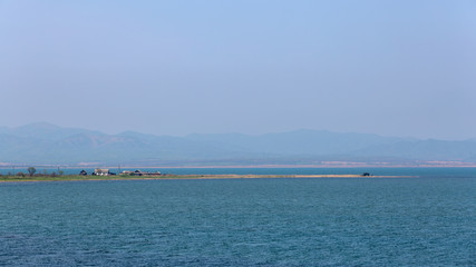 coastal spit with a house on a background of mountains