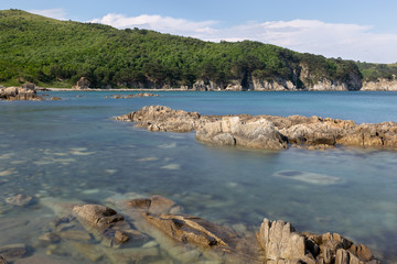 rocky bay with a rocky shore, densely growing trees on a hill