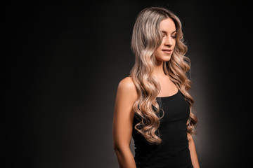 Naklejka premium Beautiful young woman with curly hair on dark background