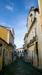 Rua estreita no centro urbano antigo de Salvador, Bahia, com muitas casas antigas coloridas.