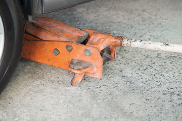 The orange hydraulic jack is lifting the car