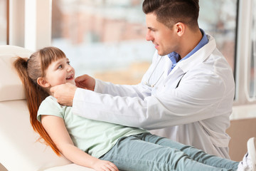 Pediatrician examining little girl in clinic
