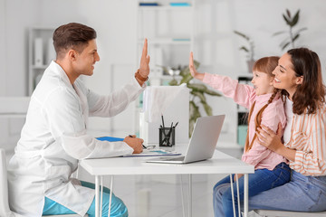Fototapeta premium Pediatrician and little girl giving each other high-five in clinic