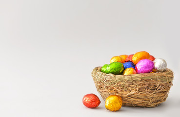 Fototapeta na wymiar Nest with sweet chocolate eggs on light background