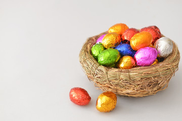 Fototapeta na wymiar Nest with sweet chocolate eggs on light background