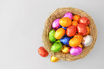 Nest with sweet chocolate eggs on light background