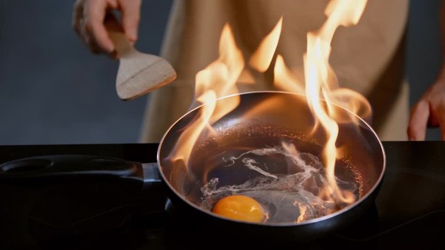 cropped view of man frying egg with flambe method