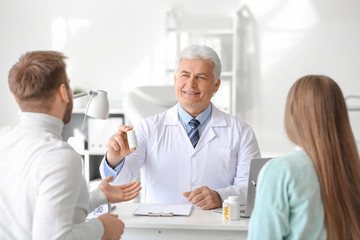 Obraz premium Doctor giving pills to young couple in clinic