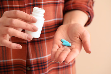 Young woman with medicine on color background, closeup