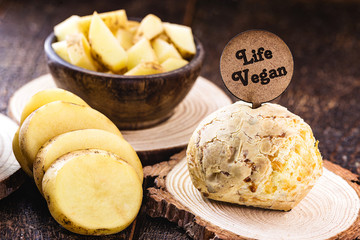 Vegan cheese bread, made without animal products, with ingredients on the side, tapioca and potatoes. Wooden sign with inscription: Vegan life.